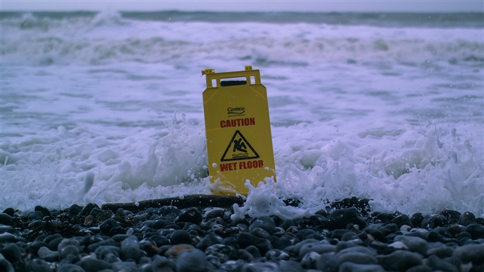 Yellow caution wet floor sign in ocean waves