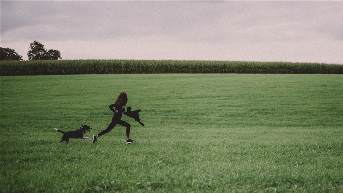 Girl and dog running in a field
