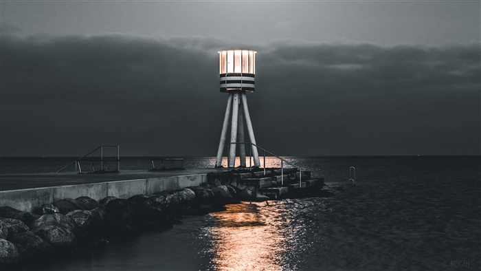 Lighthouse on a pier at night with sea and stones 4K