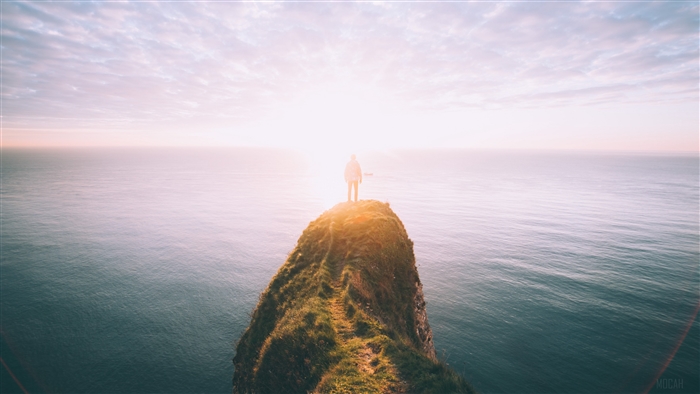 Silhouette Standing on Cliff at Sunset over Sea