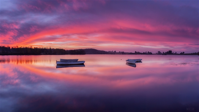 Boats on a lake at dawn with colorful sky