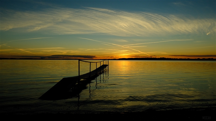 Sunset over a calm sea with a wooden pier
