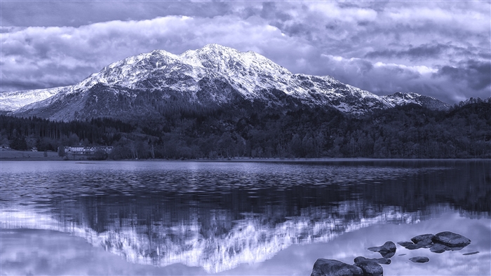 Snow-capped mountains reflected in a lake with stones