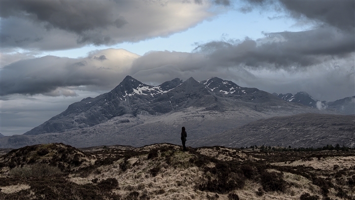 Person standing on hill overlooking mountains, Isle of Skye, UK 4K