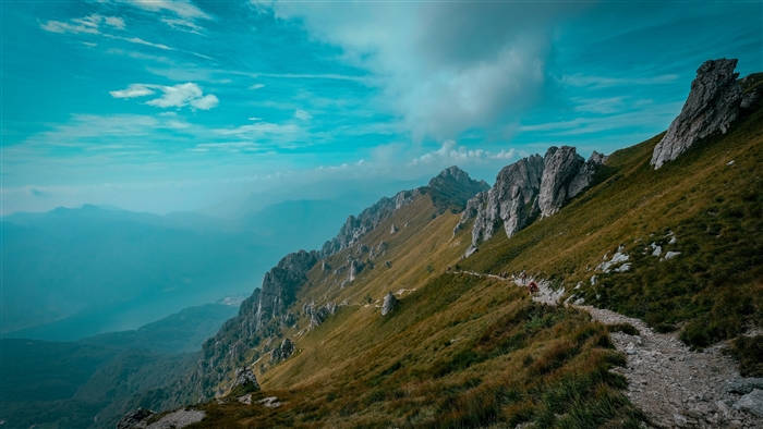 Mountain path with rocks and grass under a blue sky