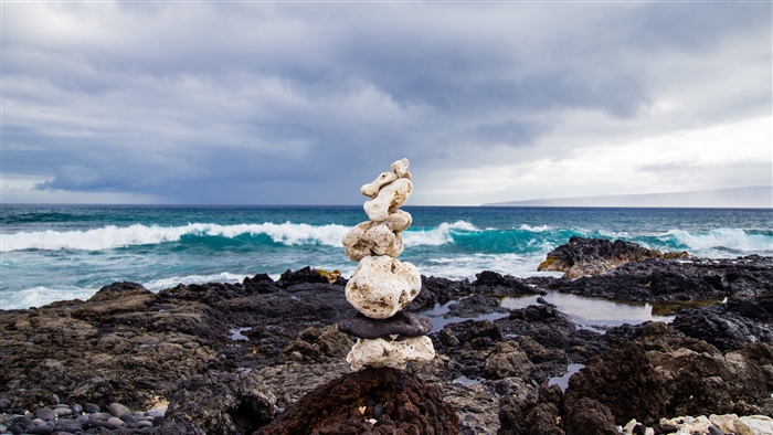 Stone cairn on a rocky beach with waves