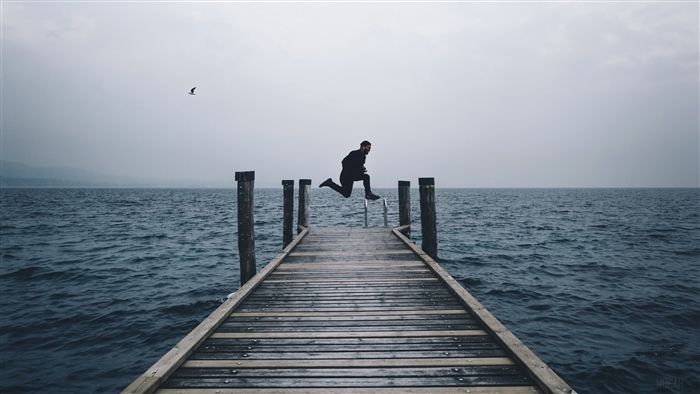 Man jumping off a pier into the sea
