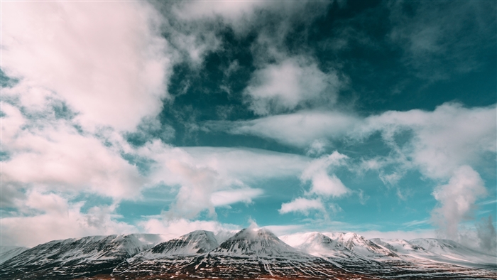 Snow-capped mountains under a cloudy sky in Iceland 4K
