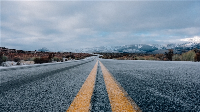 Road with yellow markings and snowy mountains