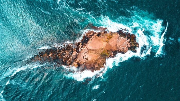Aerial view of a rocky island with waves crashing
