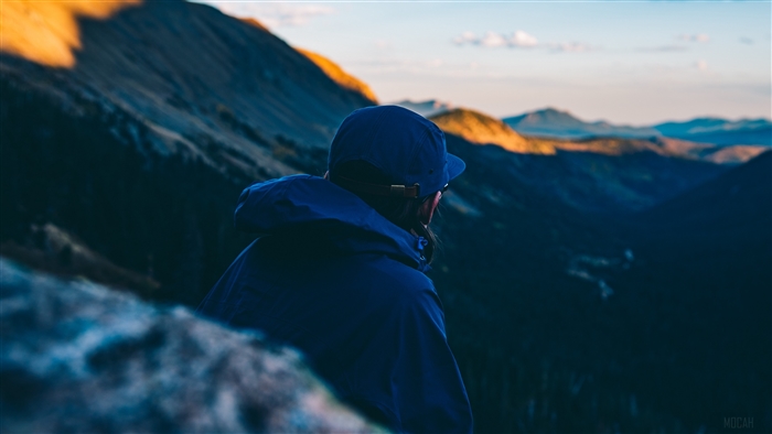 Man in blue cap and jacket overlooking mountains 4K