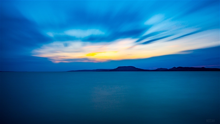 Blue sea and sky with distant mountains at sunset 4K