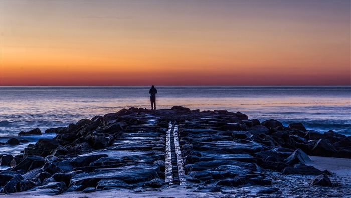 Man on a rocky shore at sunset 4K