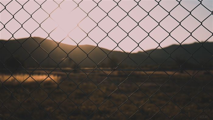 Fence in front of mountains at sunset