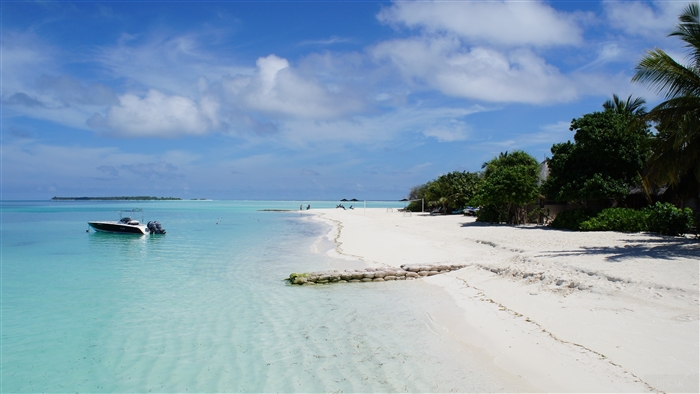 Tropical beach with boat and distant island 4K
