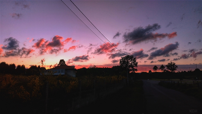 Sunset over a rural landscape with a house and road
