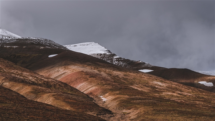 Snow-capped hills under a cloudy sky in Iceland