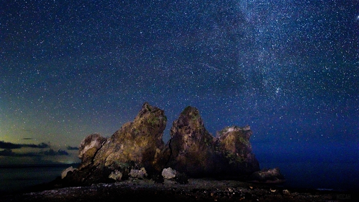 Starry sky over rocks by the ocean 4K