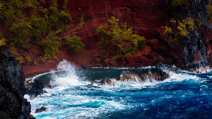 Ocean waves crashing on rocks near red sand beach in Hawaii 4K