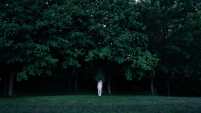 Person in white hiding under trees