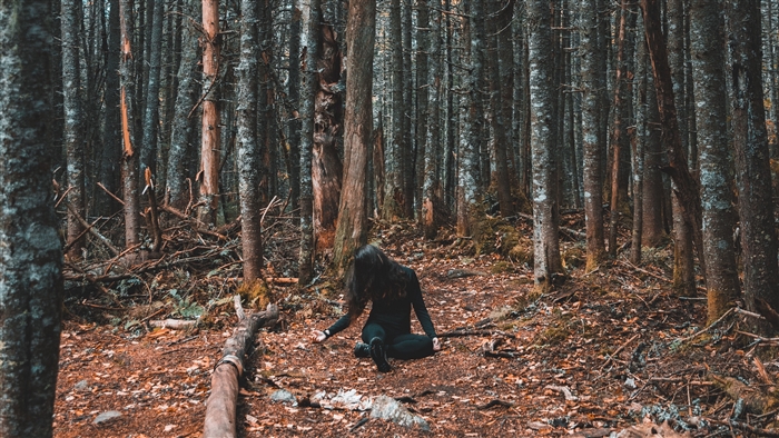 Girl sitting in a dark forest during autumn