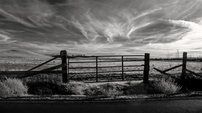 Black and white farm gate with dramatic sky