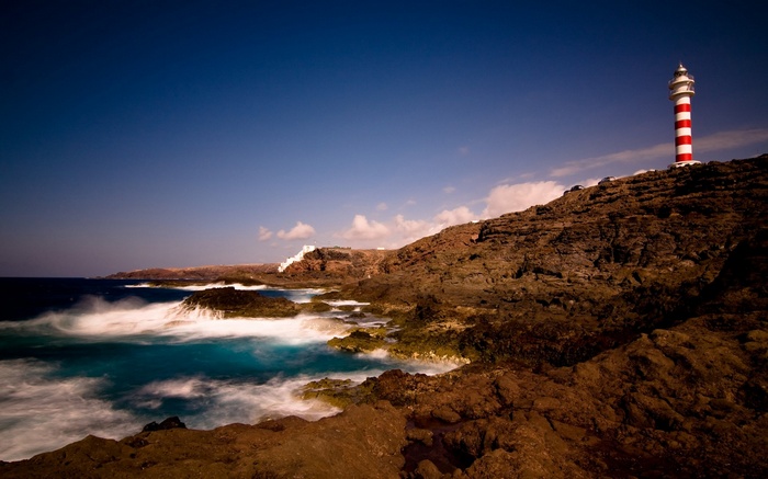 Red and white lighthouse on a rocky coast