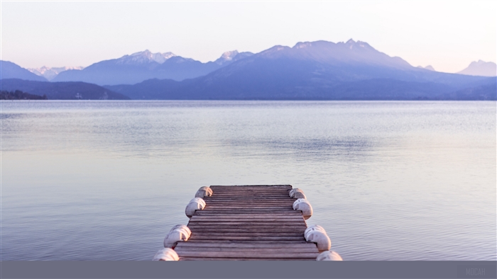 Wooden pier on a lake with mountains in the background 4K