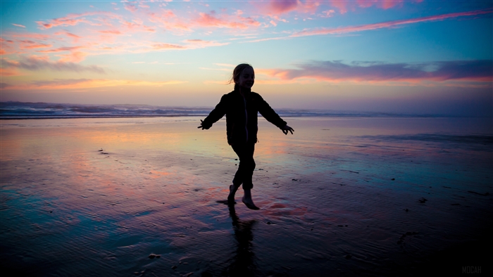 Child jumping on a beach at sunset 4K