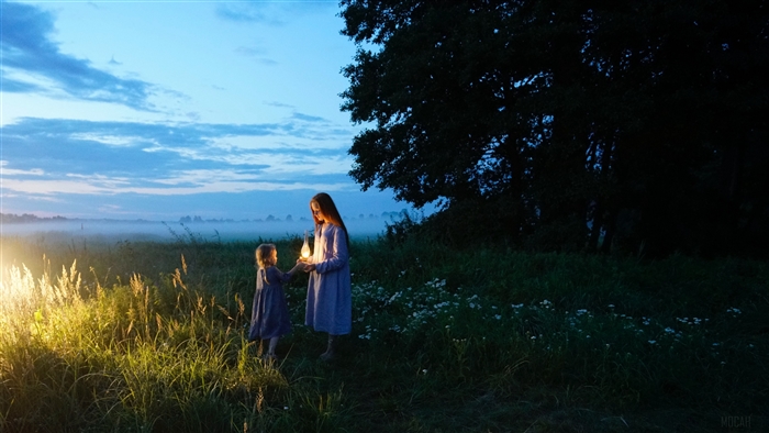 Two children holding a lamp in a field at sunset 4K