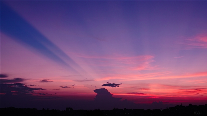 Sunset over a city skyline with crepuscular rays
