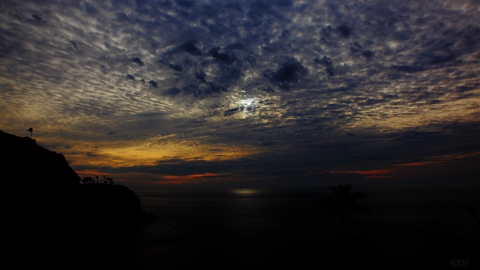 Sunset over the sea with clouds and silhouette of a hill