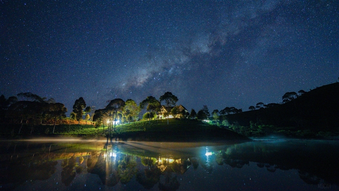 Milky Way over a lake with illuminated houses