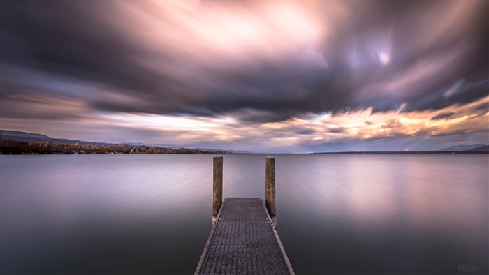 Pier on a lake at sunset with dramatic clouds