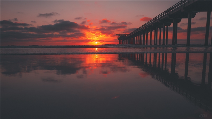 Sunset over the ocean with a pier reflection