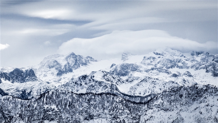 Snow-covered mountains with clouds and trees