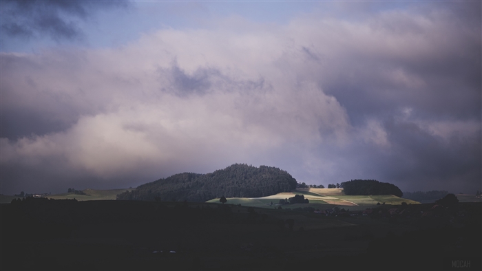 Stormy sky over rolling hills and forest