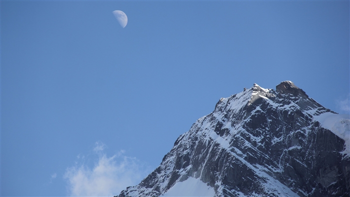 Snowy Mountain Peak with Moon in Clear Sky 4K