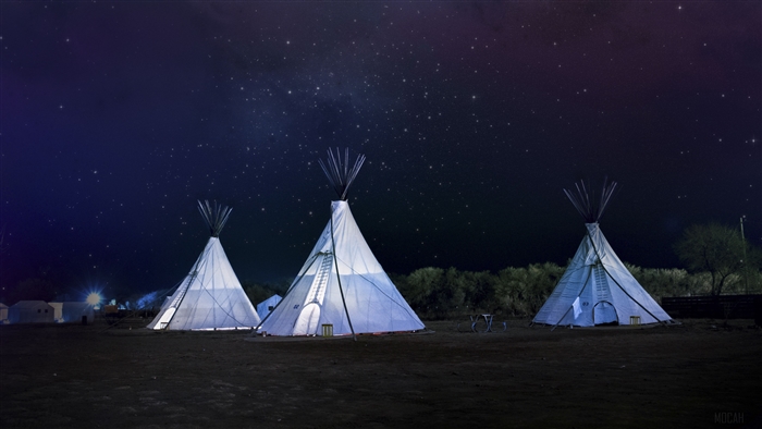 Tipi tents under a starry night sky