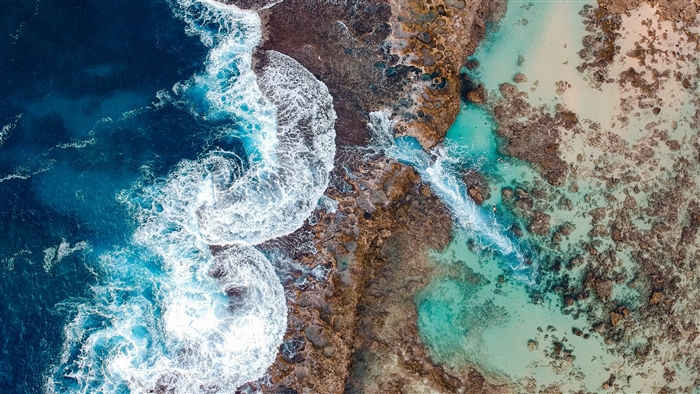 Aerial view of ocean waves crashing on rocky shore