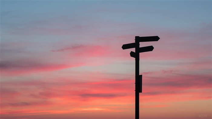 Signpost with arrows at sunset