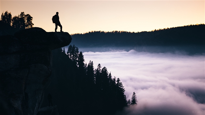 Man on precipice overlooking fog in Yosemite Valley 4K