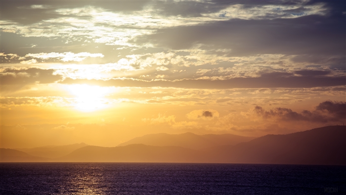 Sunset over the sea with mountains and clouds 4K