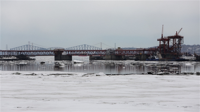Bridges over a frozen river with construction cranes