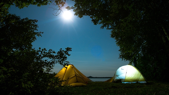 Tents camping by lake under moonlit sky