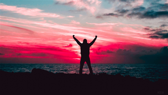 Silhouette of a man with arms raised at sunset over the sea
