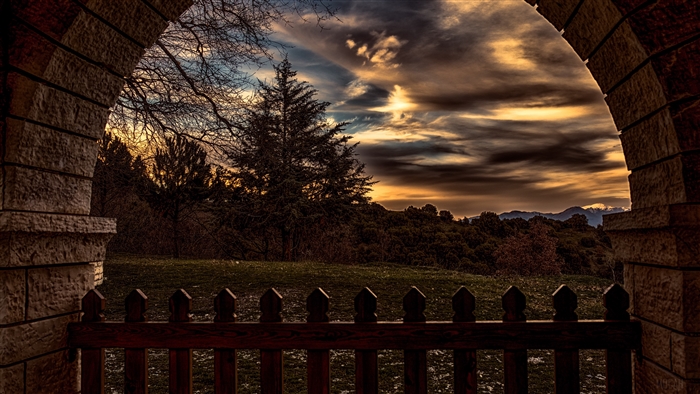 Sunset view through stone archway with fence