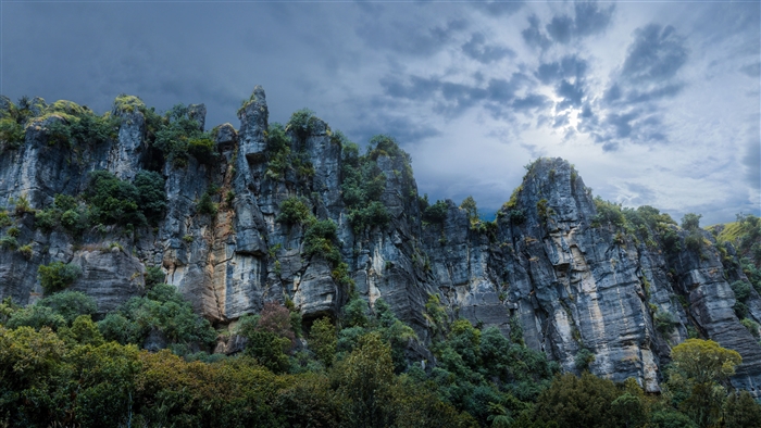 Rocky cliffs with trees under a cloudy sky