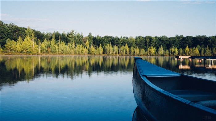 Canoe on a calm lake with trees reflecting