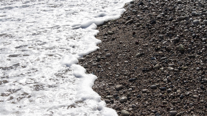Sea foam washing over pebbles on a beach